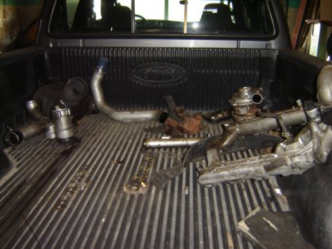 1992 Ford Bronco - Various engine components, including turbochargers, are piled in the bed of a Ford pickup truck.
