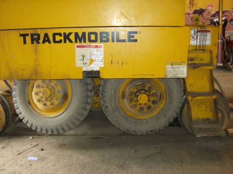 1996 Ford Probe - A yellow Trackmobile vehicle is shown from the side, with its large tires and warning labels visible.
