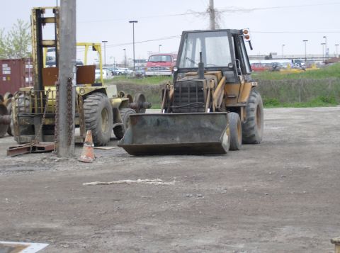 1996 Ford Probe - Heavy equipment including a backhoe loader and forklift are parked at a construction site.