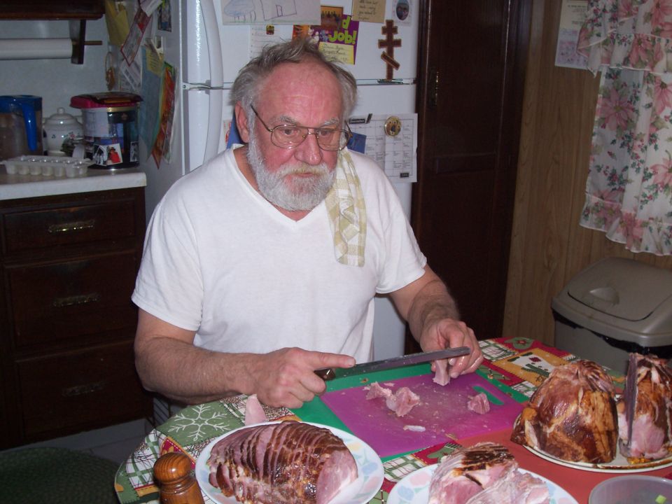 Man carving ham in a kitchen