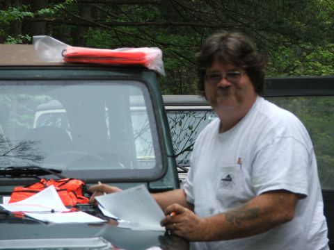1996 Ford Bronco - Man reviews documents next to a green SUV during an outdoor event.