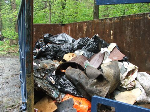 1996 Ford Bronco - A dumpster is overflowing with trash bags and assorted debris, suggesting a cleanup effort.