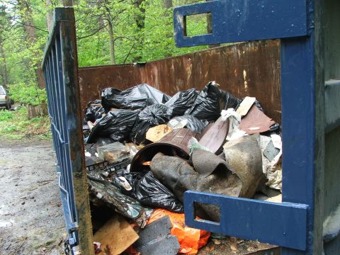 1996 Ford Bronco - A dumpster is overflowing with trash bags and assorted waste materials.