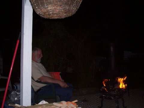1992 Ford Bronco - Man sits by a fire pit at night, with a hanging basket overhead and a red pole to his left.