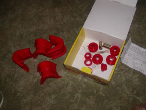 1991 Ford Bronco - A set of red polyurethane suspension bushings and associated hardware are laid out on a carpeted surface next to an open box.