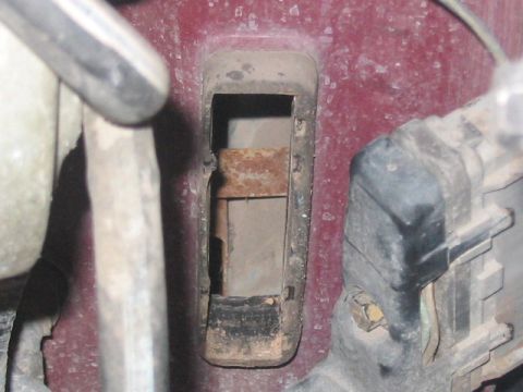 1991 Ford Bronco - Detail of a corroded metal bracket and surrounding engine components in a vehicle.