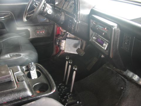 1991 Ford Bronco - The interior of a red 1991 Ford Bronco features black leather seats and a dashboard with a radio and multiple gear shifters.
