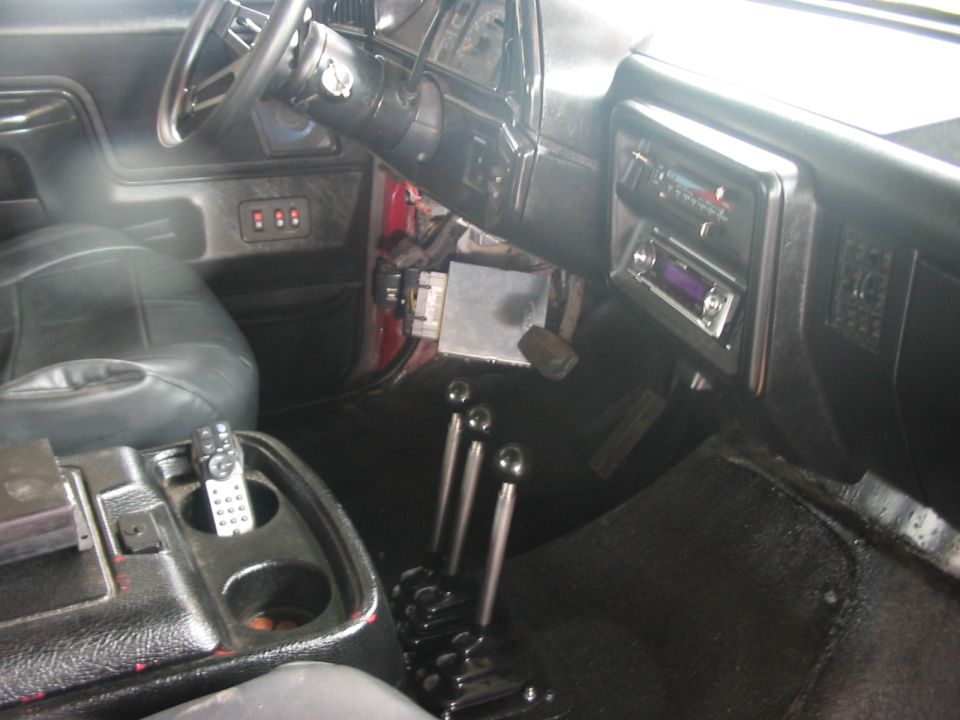 Interior of a red 1991 Ford Bronco showing black leather seats, dashboard with radio, and three gear shifters