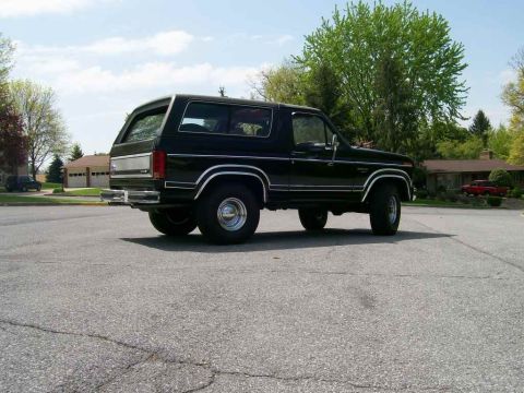 1984 Ford Bronco - Black Ford Bronco parked on asphalt, showing its rear quarter profile with chrome accents.