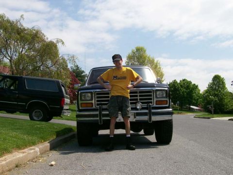 1984 Ford Bronco - A person stands in front of a classic Ford Bronco, with another Bronco visible on the side of the road.
