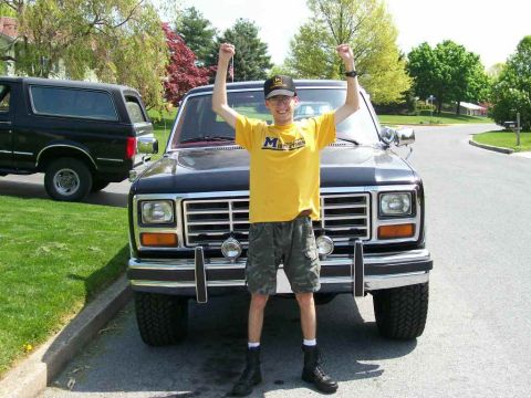1984 Ford Bronco - A man celebrates in front of a black SUV, with another black SUV visible in the background.