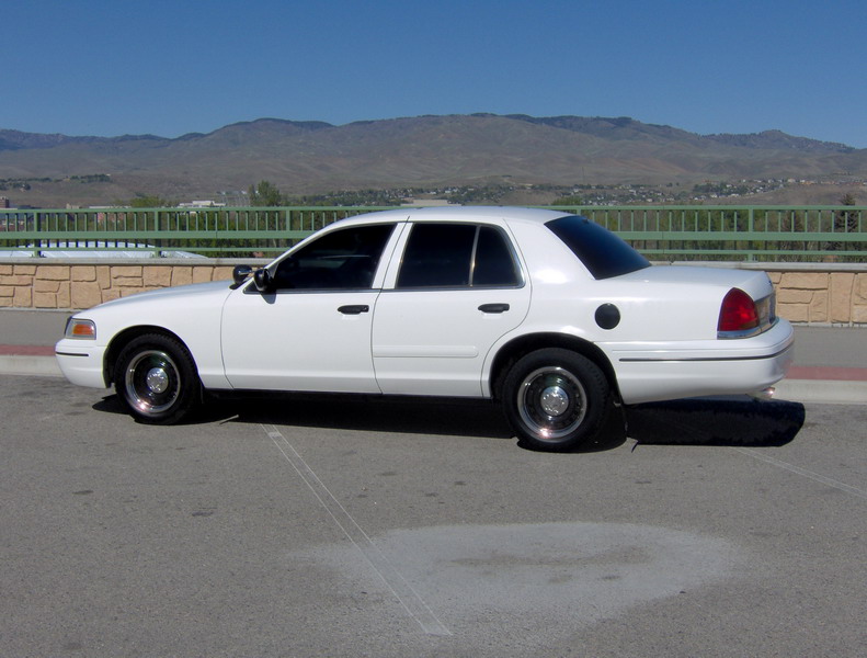 White sedan parked on asphalt with mountains in background