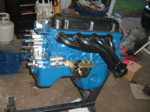1990 Ford Ranger - A blue engine block with black headers and a carburetor sits on an engine stand in a garage.