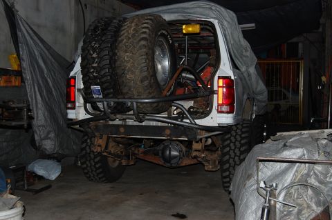 1992 Ford Explorer - A white SUV is covered by a tarp, with two large spare tires visible on the rear rack.