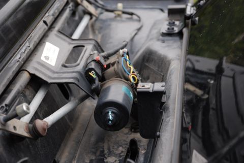1996 Ford Bronco - Close-up of a vehicle's windshield wiper motor assembly, showing electrical connections and mechanical components.