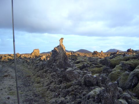 1974 Ford Bronco - A vast lava field covered in moss stretches towards distant hills under a cloudy sky.