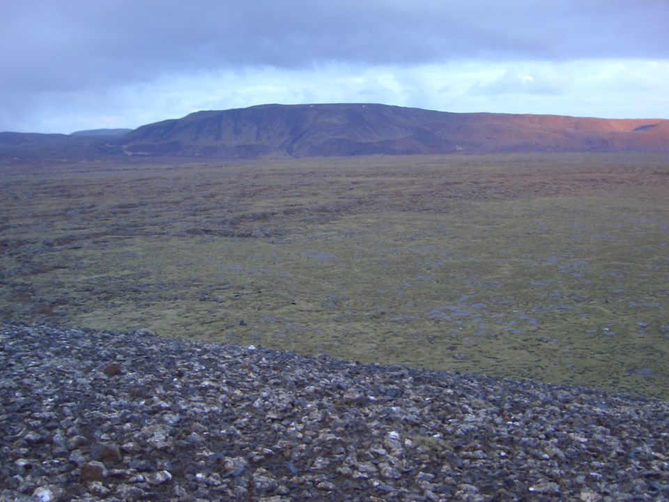 Vast, barren landscape with rolling hills and a cloudy sky