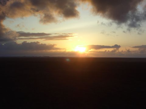 1974 Ford Bronco - The sun dips below the horizon, casting a warm glow on the clouds above a dark, open field.