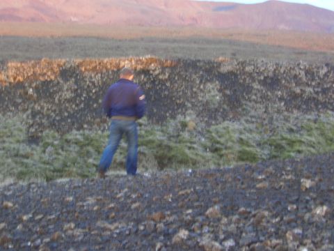 1974 Ford Bronco - A person stands in a desolate landscape with mountains visible in the distance.