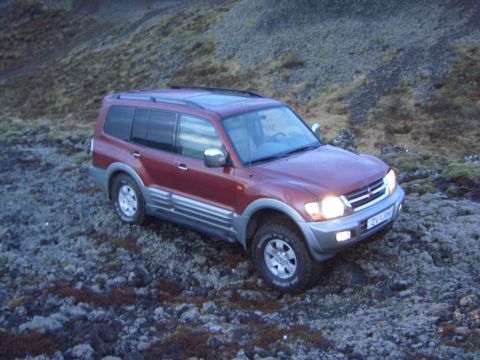 1974 Ford Bronco - This red Mitsubishi Pajero is parked on a rocky, moss-covered hillside.