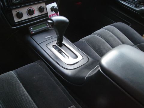 1992 Ford Crown Victoria - Center console between cloth front seats showing an automatic shifter, three rotary climate dials and a small digital display.