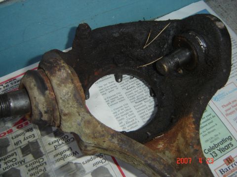 1993 Ford Bronco - A greasy and rusty front suspension knuckle is shown resting on a newspaper.