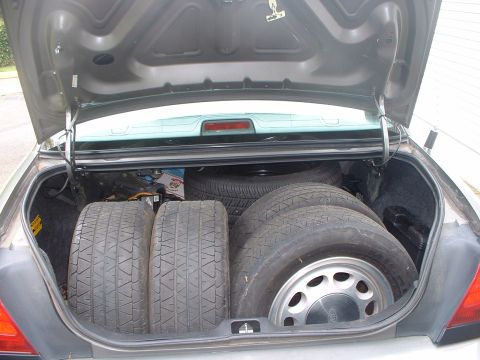 1987 Ford Mustang - The trunk of a car is open, revealing four tires and a spare tire stored inside.