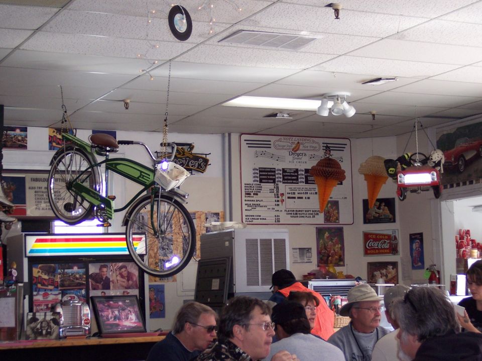 Interior of an ice cream shop with a green bicycle hanging from the ceiling and a menu board