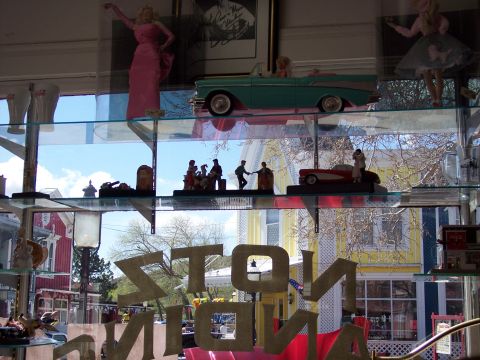 1972 Ford Ranchero - A collection of vintage car models and figurines displayed on shelves, viewed through a window.