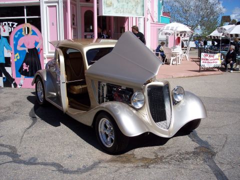 1972 Ford Ranchero - A custom hot rod is displayed outside a retro-themed diner, with its hood and door open to reveal the engine and interior.
