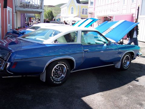 1972 Ford Ranchero - A blue coupe with a white roof and racing stripes is parked on a street with its hood open.
