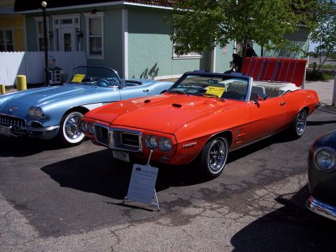 1972 Ford Ranchero - Two classic convertibles, an orange Pontiac Firebird and a blue car, are displayed outdoors.