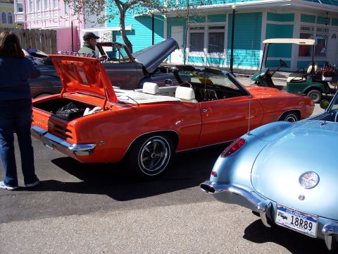 1972 Ford Ranchero - A row of colorful buildings lines the street where several classic cars are parked.
