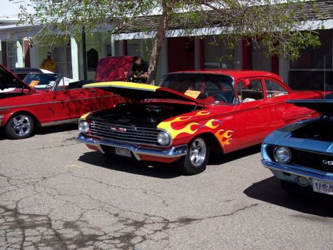 1972 Ford Ranchero - Customized red sedan with flame graphics and an open hood at a car show.