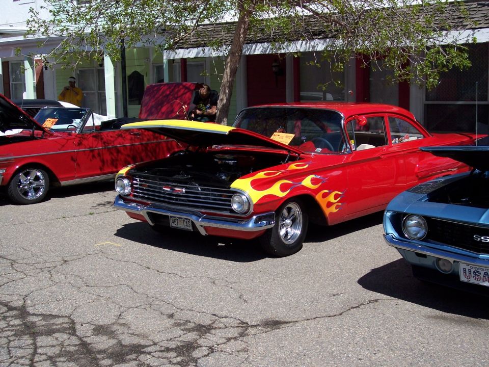 Red sedan with yellow flames and hood open, parked next to other cars
