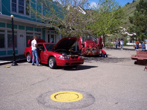1972 Ford Ranchero - Two modified cars are on display outdoors, with one having its hood and doors open.