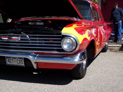 1972 Ford Ranchero - A red car with flame graphics and its hood open is parked outdoors.