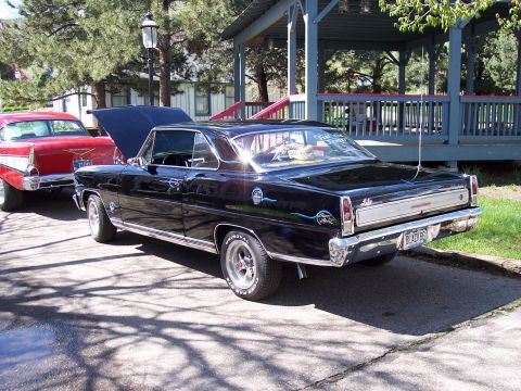 1972 Ford Ranchero - Two classic cars, a black Nova and a red Chevrolet, are parked outdoors with their hoods open.