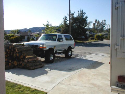 1996 Ford Bronco - Lifted 1996 Ford Bronco sits parked on a driveway next to a stack of firewood.