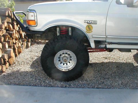 1996 Ford Bronco - The front quarter panel of a 1996 Ford Bronco is visible, with a large off-road tire and custom bumper.