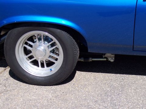 1972 Ford Ranchero - Close-up of a blue vehicle's side, focusing on the wheel and suspension components.