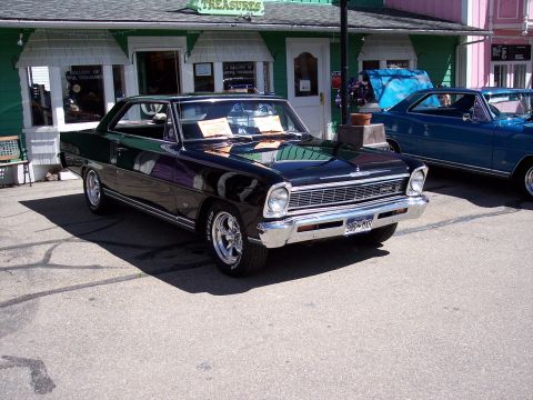1972 Ford Ranchero - A black 1967 coupe is parked in front of a building with a blue car behind it.