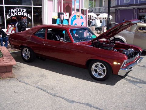1972 Ford Ranchero - A red coupe with its hood open, parked on a street with other vehicles and buildings in the background.