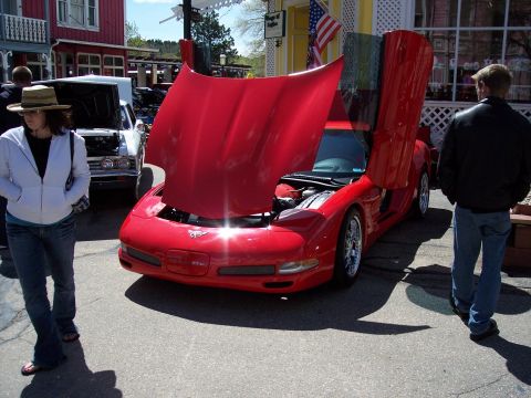 1972 Ford Ranchero - A red sports car is displayed with its hood and doors open, attracting attention at an outdoor event.