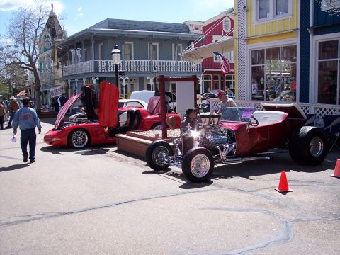 1972 Ford Ranchero - Two custom cars are displayed on a street in front of historic buildings, with people milling around.