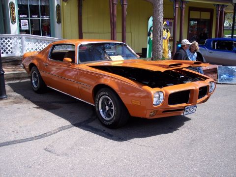 1972 Ford Ranchero - This orange muscle car, likely from the early 1970s, is parked in front of a building with visible text.