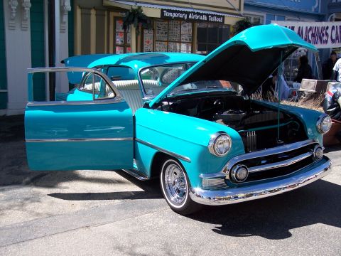 1972 Ford Ranchero - A vintage turquoise coupe is displayed with its doors and hood open, parked on a street in front of shops.