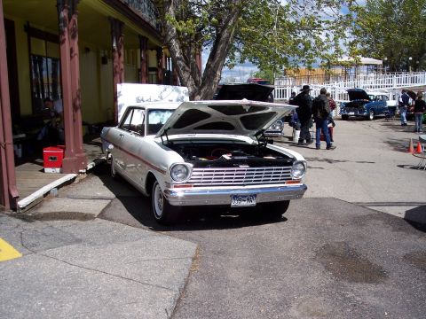 1972 Ford Ranchero - A white coupe with its hood open is parked in front of a building with other cars in the background.