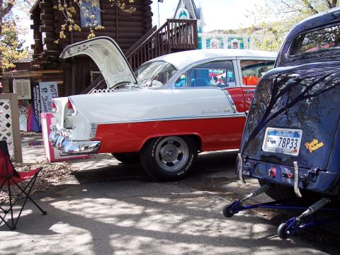 1972 Ford Ranchero - A two-tone red and white 1955 Chevrolet Bel Air is parked next to another vehicle, with its hood open.