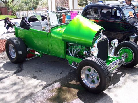 1972 Ford Ranchero - A custom green hot rod pickup truck is displayed with its hood open, revealing the engine, next to another vehicle.